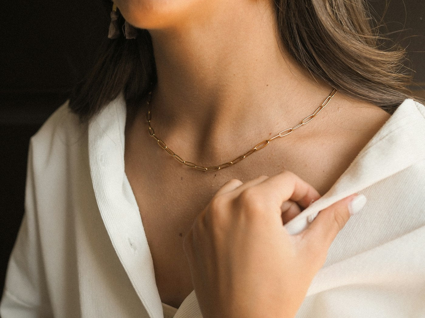 Une femme portant un chemisier blanc et un collier doré